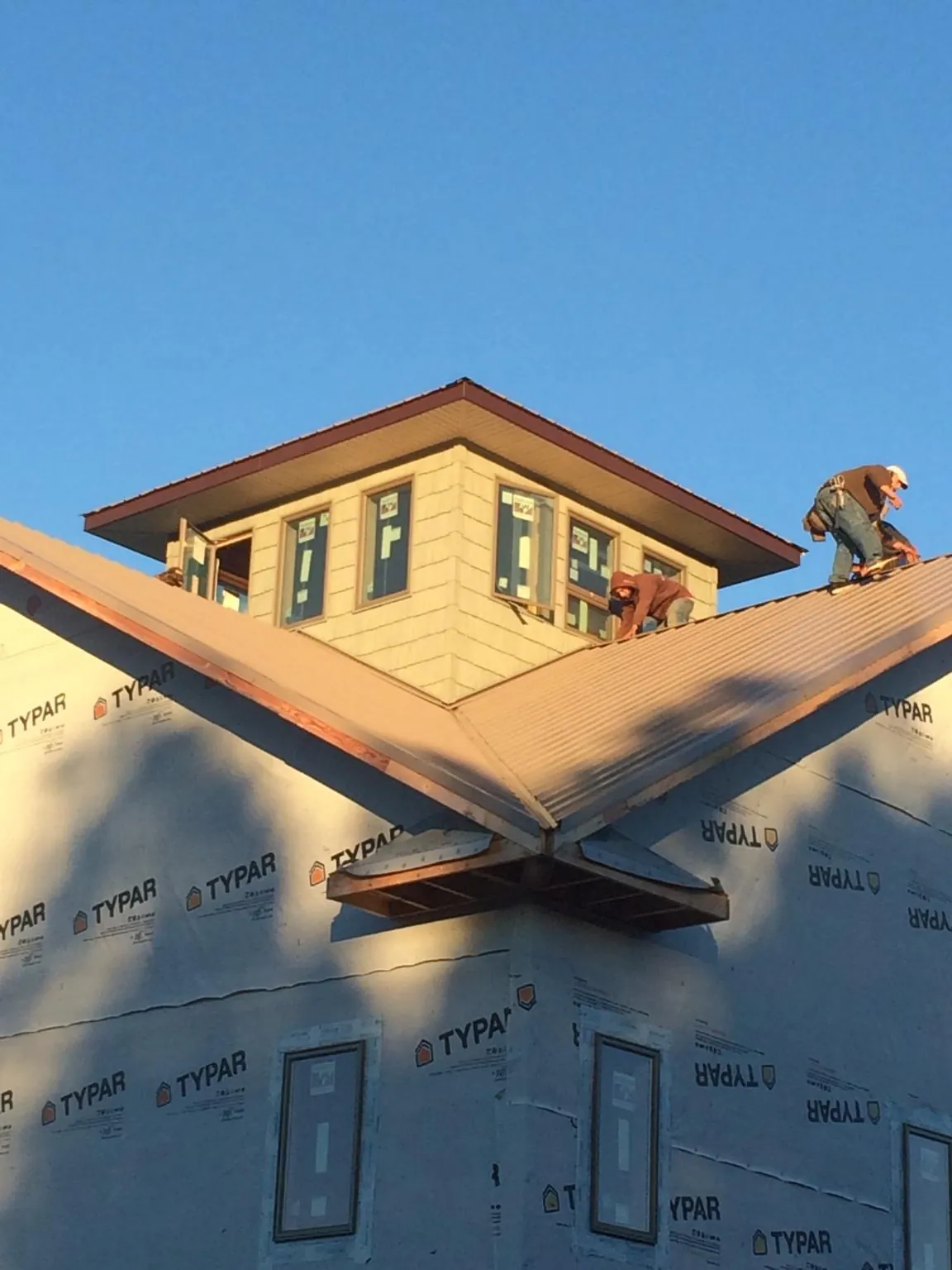 Roofers working around a rooftop cupola on a new metal roof at sunset — Roof Waterproofing in Addison by Roofing Brothers